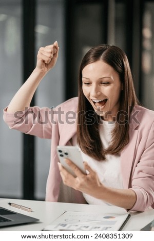 Overjoyed charming excited caucasian woman business woman worker using smartphone and laptop working in office, feeling happy.