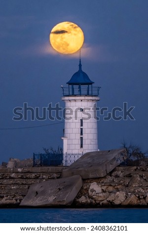 MANGALIA, ROMANIA - DECEMBER 26, 2023. Full moon sunrise near the Genoese lighthouse on the Black Sea. The last full moon rise of 2023 Royalty-Free Stock Photo #2408362101