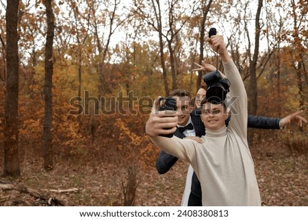 wedding photographer with bride and groom taking selfie with mobile phone in nature