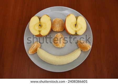 Pieces of fruits organised as a smiling face on a plate