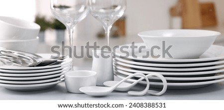 Set of clean dishware, glasses and cutlery on table in kitchen Royalty-Free Stock Photo #2408388531