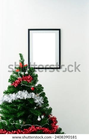Empty black picture frame with christmas tree with ball on white wall background