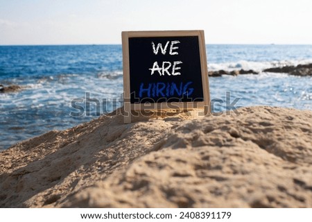We are Hiring symbol. Concept words We are Hiring on black chalk blackboard blocks. Beautiful sea background. Business and We are Hiring concept. Copy space.