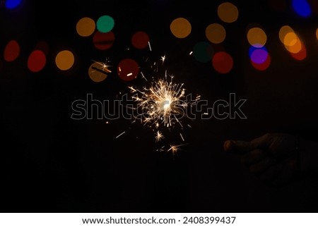 Sparkler or Fuljhadi in hand with dark black background with colorful bukeh to celebrate the festival of Diwali. Royalty-Free Stock Photo #2408399437