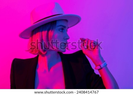 Fashionable and stylish woman in trendy jewelry with stones and diamond watches. elegant model in white hat, red lips makeup and colorful lighting filters. Fashion model in profile.