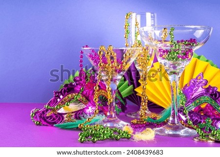 Mardi gras cocktails set. Colorful purple, yellow, green martini champagne wine cocktail glasses for Mardi gras party bar with carnival decor and orleans masquerade masks Royalty-Free Stock Photo #2408439683