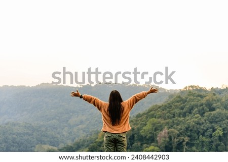 Happy woman raiseก open arms arms with mountain forest nature background, lifestyle and healthy confidence relax woman concept. Royalty-Free Stock Photo #2408442903