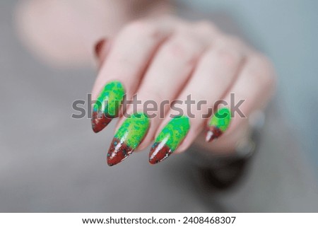 Female hands with long nails and green and brown thermo manicure	