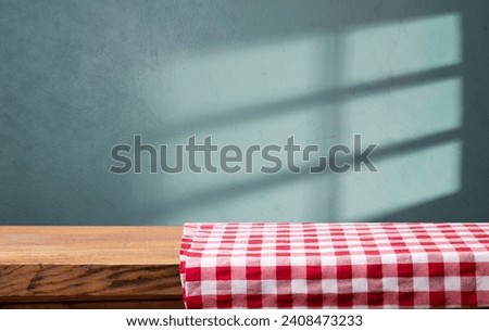 Empty wooden deck table and red checked tablecloth over mint wallpaper background. High quality photo