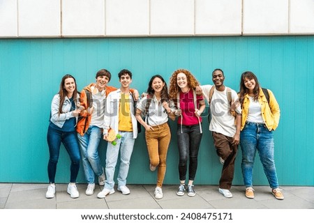 Diverse college students standing together on a blue wall - Photo portrait of multiracial teenagers in front of university building 