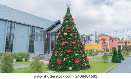 Picture of a large green Christmas tree The tree is decorated with giant red gift bows. There are stars twinkling Located among modern vacation homes.