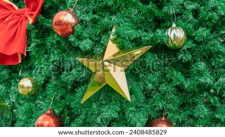 Picture of a large golden star Decorated on the Christmas tree, it looks bright and shiny, surrounded by red and gold balls. Welcoming the New Year's Festival