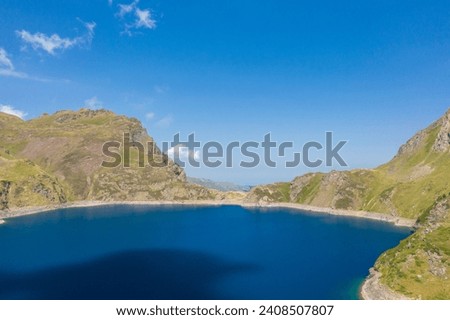 The blue lake in the green countryside in the mountains , Europe, France, Occitanie, Hautes-Pyrenees, in summer on a sunny day.