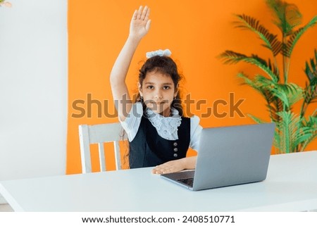School girl sitting at desk with laptop at lesson at school