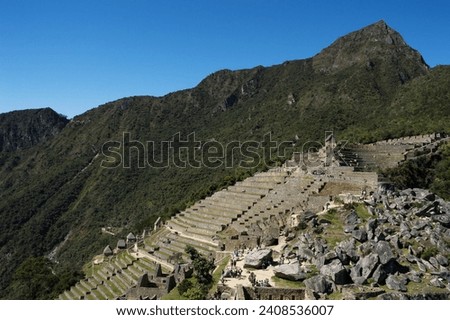 mountain with space full of huge cut stones next to terraces in sector of the citadel of Machu Picchu