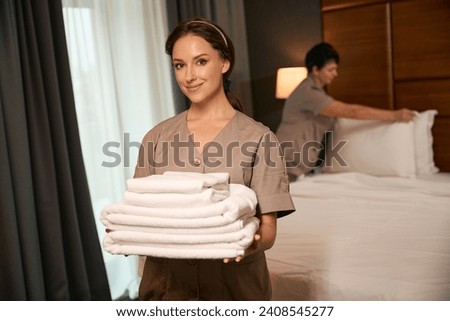 Team of maids busy with work in hotel room Royalty-Free Stock Photo #2408545277