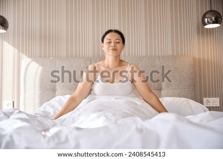 Relaxed female meditating in her suite after morning awakening Royalty-Free Stock Photo #2408545413