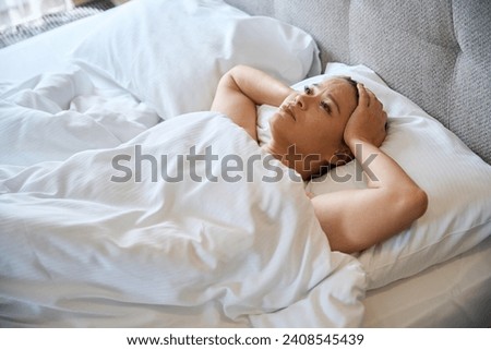 Female is feeling uneasy after morning awakening in her bedchamber Royalty-Free Stock Photo #2408545439