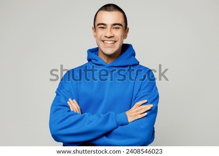 Young smiling happy cheerful middle eastern man he wears blue hoody casual clothes hold satisfied hands crossed folded look camera isolated on plain solid white background studio. Lifestyle concept