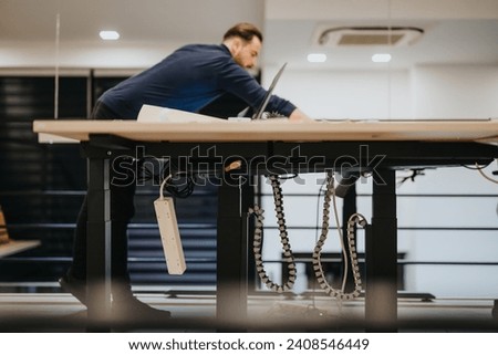 Male employee catching up deadline project. He is working alone on the project, late at night in modern office. Royalty-Free Stock Photo #2408546449