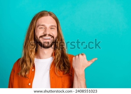 Portrait of young cheerful guy wear orange shirt point finger good proposition to customers isolated on aquamarine color background
