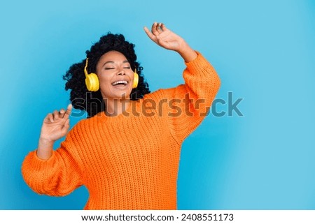 Photo portrait of pretty young girl dancing listen music radio stereo wear trendy knitwear orange outfit isolated on blue color background