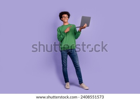 Full length photo of funky positive guy wear green pullover eyeglasses pointing finger modern device isolated purple color background