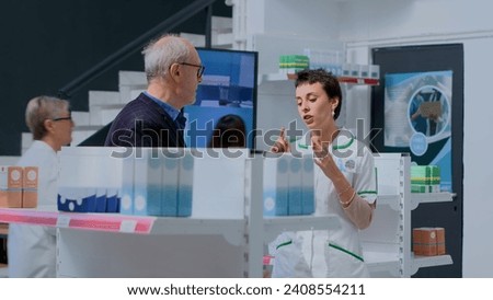 Aged client in need of prescription illness prevention drug informations in apothecary, asking knowledgeable druggist. Pharmacy employee helping older customer with medical expertise Royalty-Free Stock Photo #2408554211