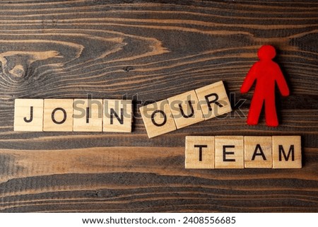 Wooden figures and wooden cubes with Join Our Team letters on a wooden table. Human resources management concept