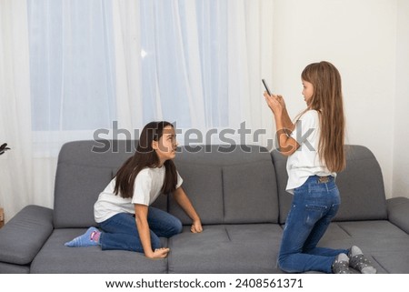 Two cute Caucasian blonde girls sisters holding cell phone and laughing.