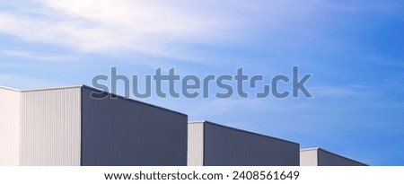 Row of modern black and white corrugated metal industrial factory Buildings against blue Sky background, Panoramic and perspective side view