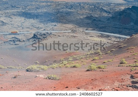 A bus moves in volcanic landscape on the island of Lanzarote, Canary Islands, Spain