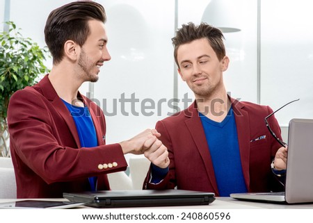 Two succesfull brothers twins handshaking at the office