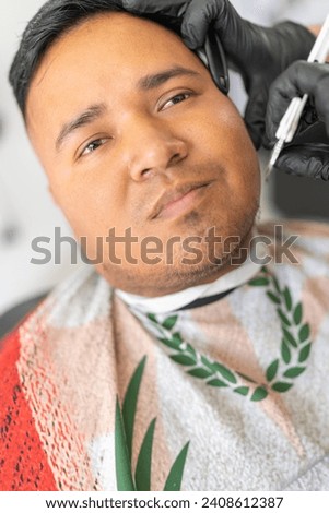 Vertical close-up of the face of a client attended in a barber shop Royalty-Free Stock Photo #2408612387