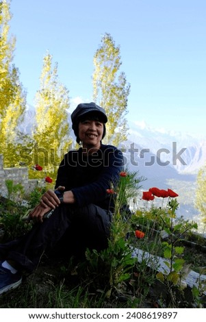 An Asian female tourist enjoy taking a picture with red poppies at a hotel in Hunza Valley in Gilgit-Baltistan region of Pakistan.