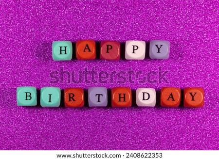 Happy Birthday written with wooden cubic beads on a purple background. Image for decoration, ornamental with blocks spell