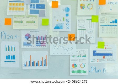 wall with various colorful business charts, graphs, and sticky notes, indicating planning or brainstorming activities.