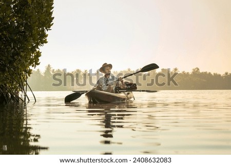 Kerala travel and tourism concept photo Young man kayaking on the River, Tourist canoeing on Kavvayi Island Kannur, water adventure image Royalty-Free Stock Photo #2408632083