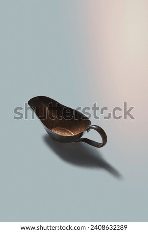 Bronze retro sauceboat with shadows on a white background, copy space. Vintage kitchenware. Royalty-Free Stock Photo #2408632289