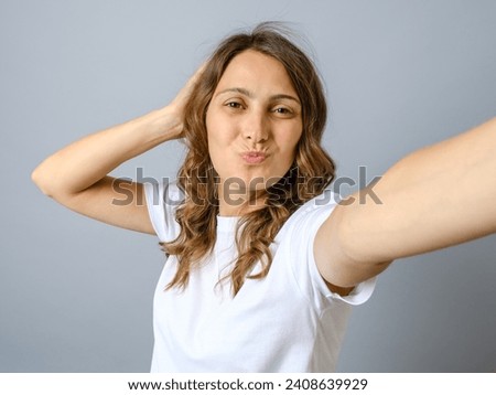 Young woman laughing while taking selfie photo isolated over gray background