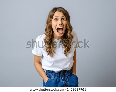 Portrait of young pretty surprised woman with opened mouth isolated on a gray background Royalty-Free Stock Photo #2408639961