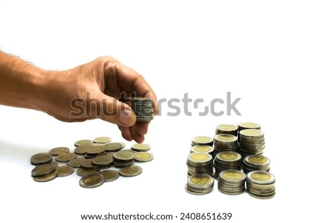 A man's hand takes coins from a pile of coins on a table for counting. Coins with a denomination of 1000 rupiah.