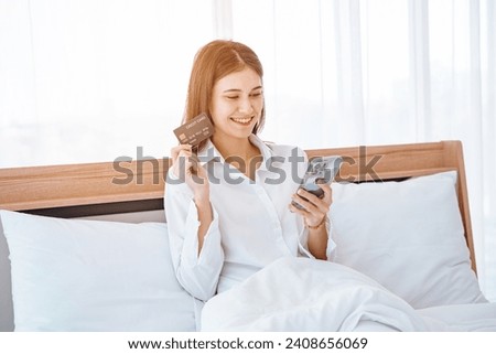 Young woman  lying in bed using mobile cell phone credit bank card shopping online rest relax spend time in bedroom lounge home in own room hotel wake up dream be lost in good mood.