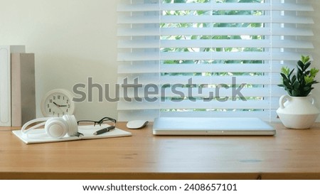 Creative workplace with laptop, picture frame, flower pot and stationery on wood table.