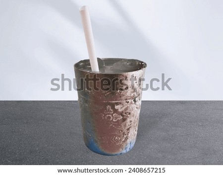 In the picture is a silver aluminum drinking glass filled with water and ice. It has a white drinking straw. It is delicious and refreshing to drin
