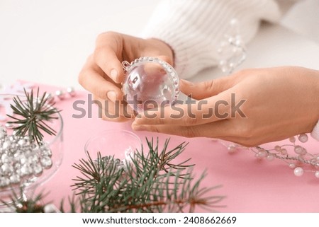 Woman decorating Christmas ball with rhinestones on table