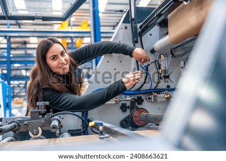 Smiling engineer looking at camera while repairing a cnc machine in a modern logistic factory