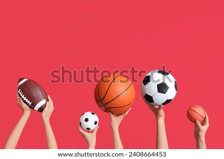 Female hands with basketball and soccer balls on red background