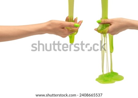 Green slime toy in woman hand with green nails isolated on a white background.  Royalty-Free Stock Photo #2408665537