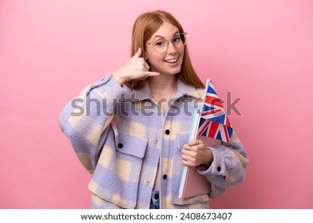 Young redhead woman holding an United Kingdom flag isolated on pink background making phone gesture. Call me back sign